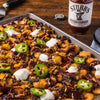 A close-up of a plate of tater tots topped with Stubbs BBQ sauce, cheese, jalapenos, and sour cream.