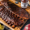A close-up of a plate of Stubbs BBQ ribs with a bottle of Stubbs BBQ sauce.
