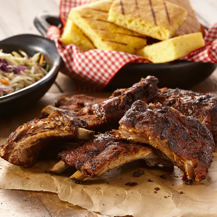 A close up of a plate of ribs and cornbread.