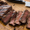 A close-up of a sliced steak on a wooden cutting board.
