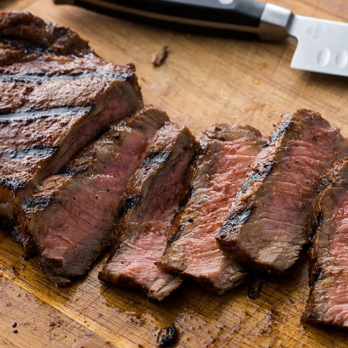 A close-up of a sliced steak on a wooden cutting board.