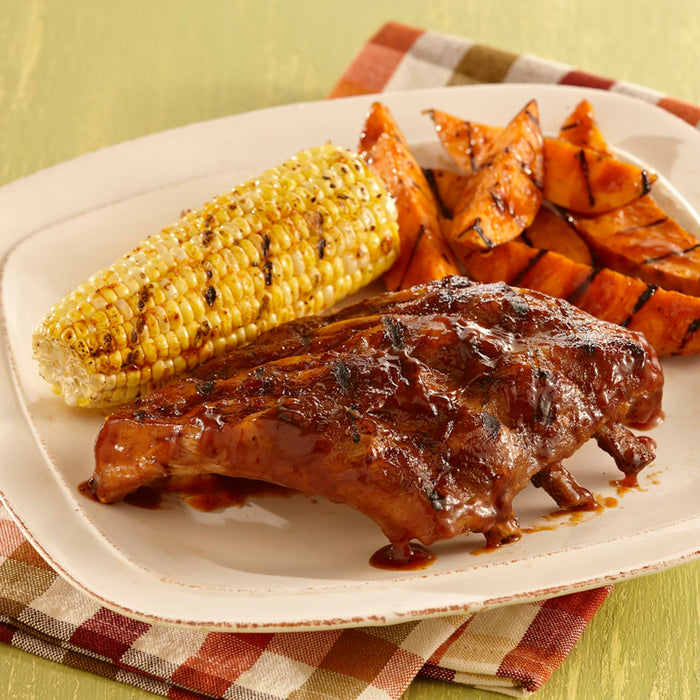 A plate of barbecue ribs, corn on the cob, and sweet potato fries.