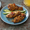 Three chicken wings are on a blue plate with cucumber slices.