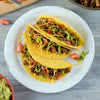 A plate of delicious tacos filled with seasoned ground beef, lettuce, tomatoes, and shredded cheese.