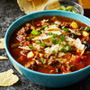 A bowl of chili topped with tortilla chips and green onions.