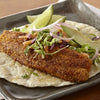 A delicious fish taco with avocado, cabbage, and lime wedges on a gray plate.