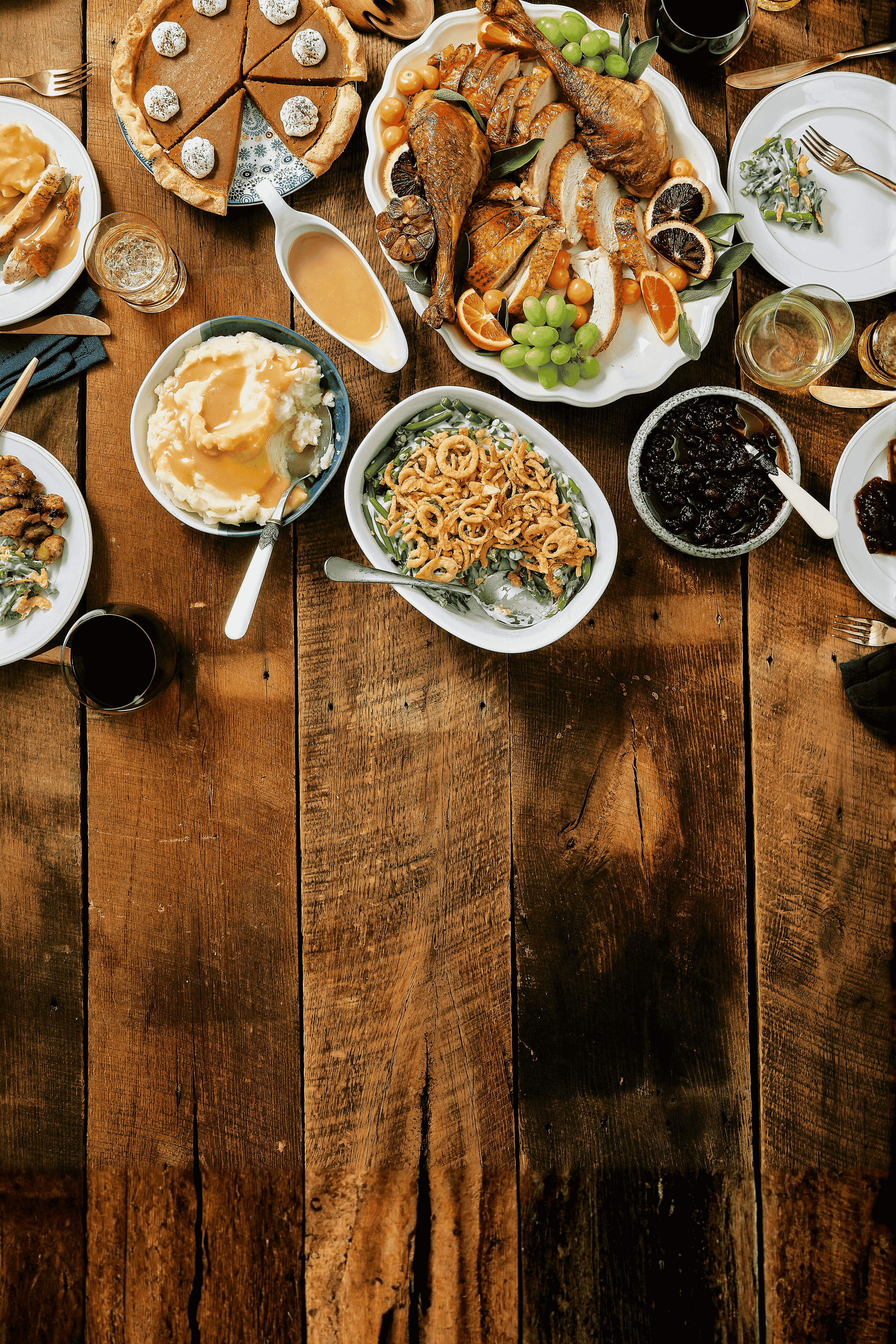 Diverse food dishes on a wooden table with various utensils.