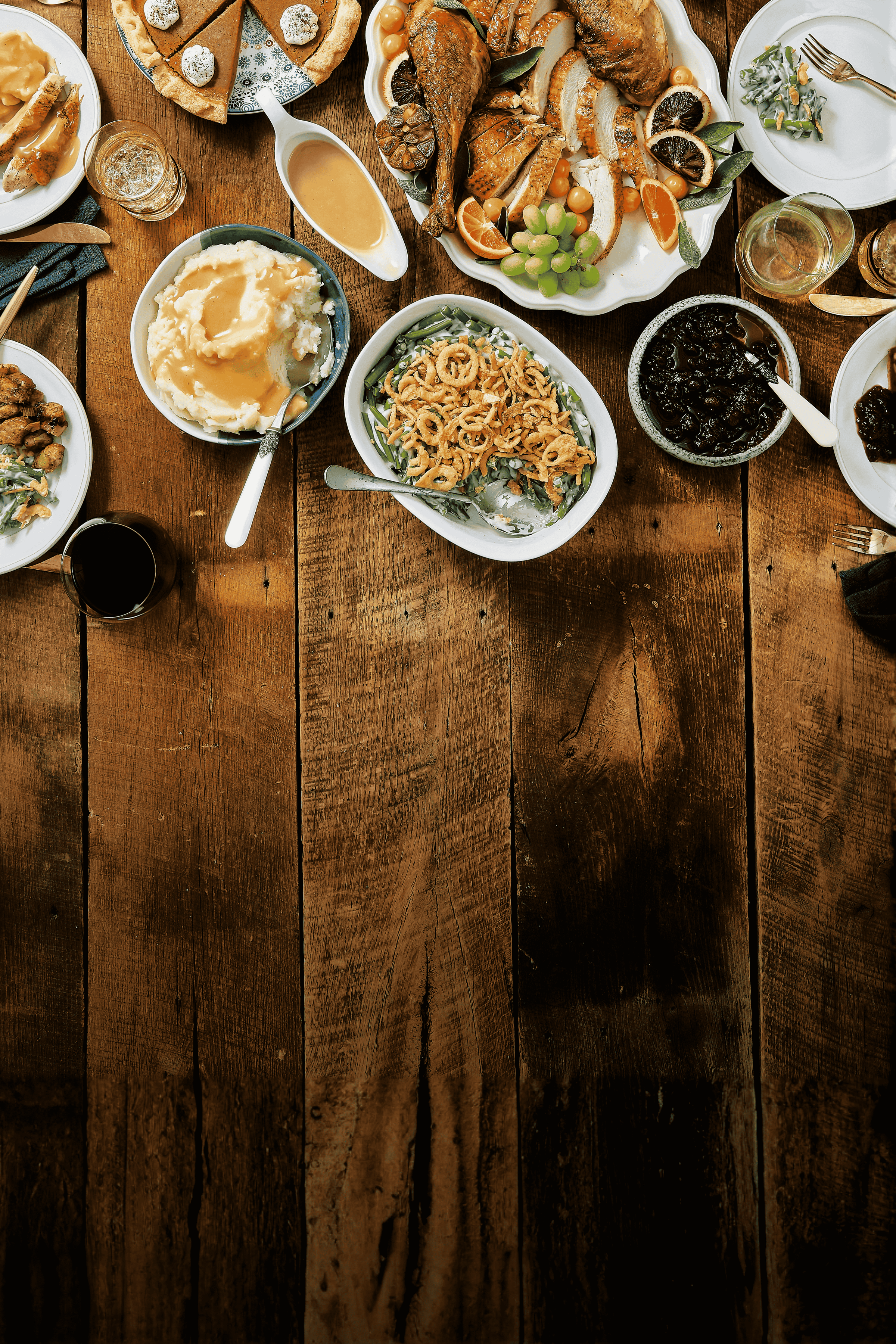 Wooden table with various dishes of food including pasta, salad, and bread.