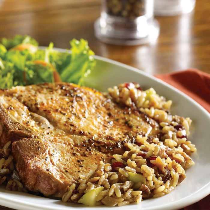 A plate of grilled pork chops with wild rice pilaf and a side salad.
