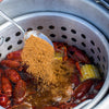 A metal pot filled with crawfish, corn, and spices.